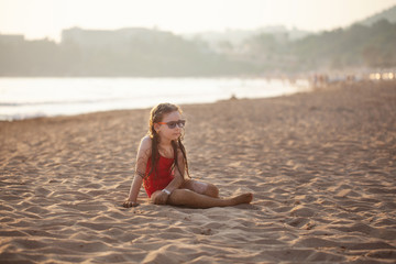 Fototapeta na wymiar young girl in glasses plays on the sand beach