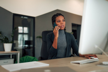 Portrait of a dedicated office worker talking on mobile phone at workplace.
