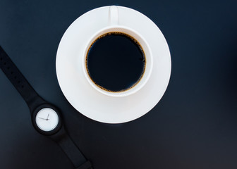 White cup of coffee and black hand watch on black background  