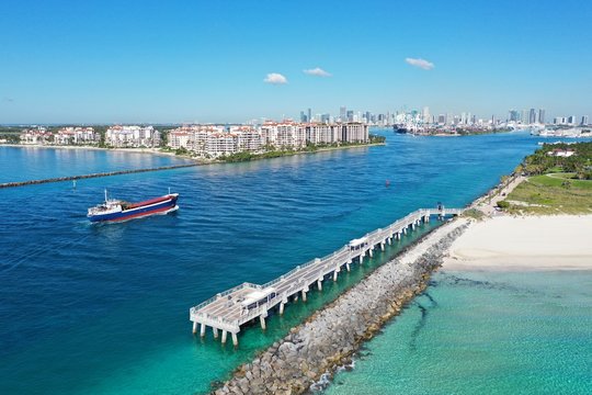 Aerial view of small cargo ship entering Government Cut off Miami Beach, Florida on clear sunny summer morning.