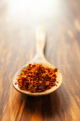 Dried Spicy Crushed Chili Peppers on a wooden spoon. Vertical photo with plenty of free space.