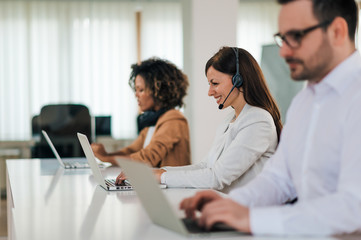 Business people working on their laptop computers, side view.