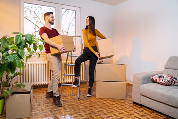 Boyfriend and girlfriend moving in holding boxes in arms 
