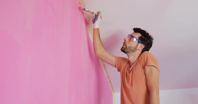 Pittore sta pitturando la parete di una stanza di rosa