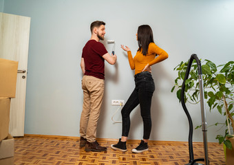 Young attractive couple moving in and painting the walls , copy space 