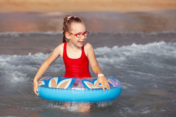 Obraz premium young girl in glasses plays in the water on an inflatable donut in a hot sunny summer