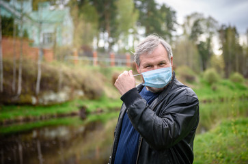 Happy man on a nature walk by the river. The man removes the medical mask from his face.