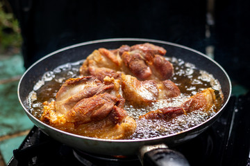 A close-up shot of streaky pork cooking in a frying pan has hot oil and it looks delicious.