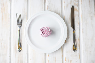 plate with fork and knife with rose cacke on it.