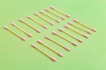 Bamboo cotton buds with pink cotton on a green background. Natural elements. Zero waste. Selective focus