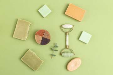 Natural soap and face roller on geen background. Self-care. Flat lay