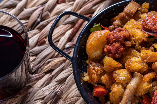 Extremadura crumbs, a typical dish from Extremadura, breadcrumbs, bacon, red and green peppers, garlic and paprika, with a glass of red wine