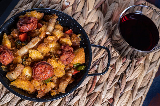 Extremadura crumbs, a typical dish from Extremadura, breadcrumbs, bacon, red and green peppers, garlic and paprika, with a glass of red wine