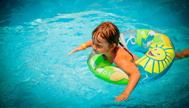 Top view of beautiful child girl in swimming pool relax swim on inflatable ring. Summer holiday, vacation and happy childhood. Horizontal image.