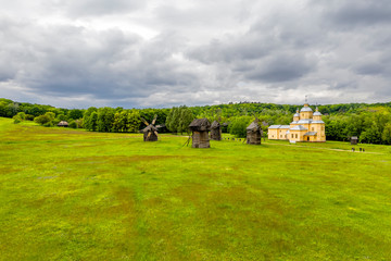 Fototapeta premium Old wooden orthodox church near the windmills
