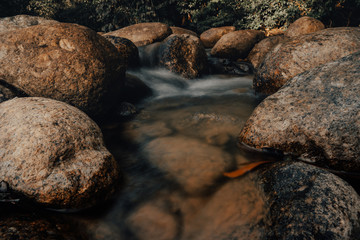Fototapeta na wymiar Smooth waterfall on dark-colored rocks