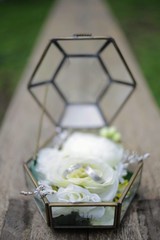 Fototapeta na wymiar Geometric Hoop Bouquet and Hexagonal Arch for an Outdoor Ceremony and Glasshouse Wedding Reception with rings on white rose.
