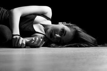 Fototapeta na wymiar Black and white portrait of young woman lying down on a floor