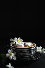 still life, cup of coffee with marshmallows and spring flowers on a black background, empty space for text