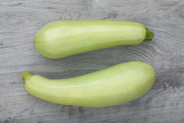 Two fresh courgette placed on a grey wooden background. Flat lay view. Close up. Concept of healthy vegan food.
