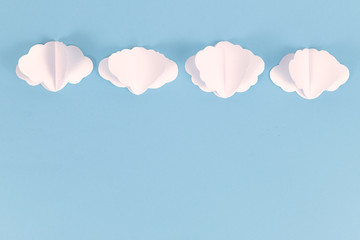 White paper craft clouds on top of blue sky background with blank copy space