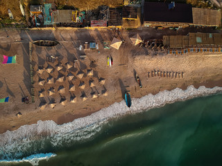 Aerial view of amazing beach with umbrellas and turquoise sea at sunrise. Black Sea at Vama Veche, Romania