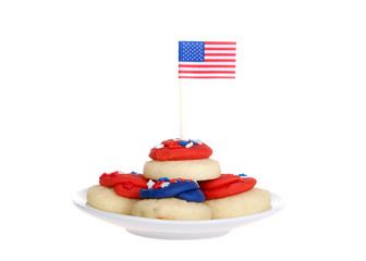 small white porcelain plate with vibrant colorful patriotic bite sized frosted sugar cookies, tiny flag in top cookie. isolated on white