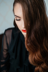 Close up portrait of young lady beautiful girl with dark long hair in evening dress with closed eyes. Eyelashes and red lips selective focus.