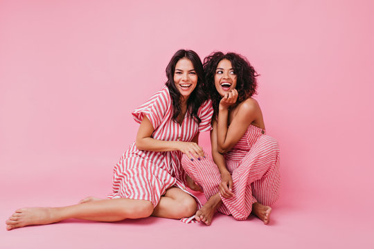 Two Girls With Dark Hair, One With Straight And Other With Curly, Dressed In Soft And Lovely Pajamas, Having Fun And Playing, Looking At Camera