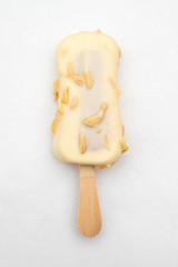ice cream on a wooden stick in white chocolate glaze with nuts on a white background