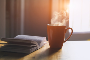 cup of fresh tea or morning coffee and open book at home on wooden table, reading book and drinking coffee concept