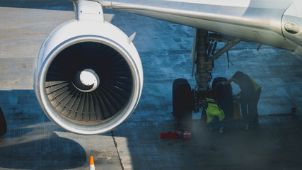 Ground service crew repairing and preparing airplane for flight in airport