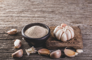 garlic and garlic powder on old wood, close up image