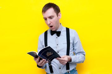 handsome shocked man in shirt and suspender reading usa constitution and independence declaration on yellow background