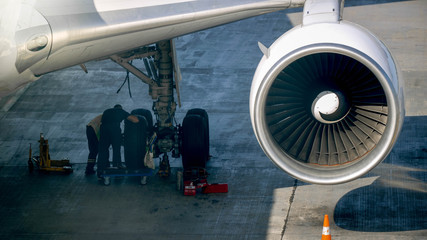 Photo of maintenace ground crew checking airplane chassis before flight