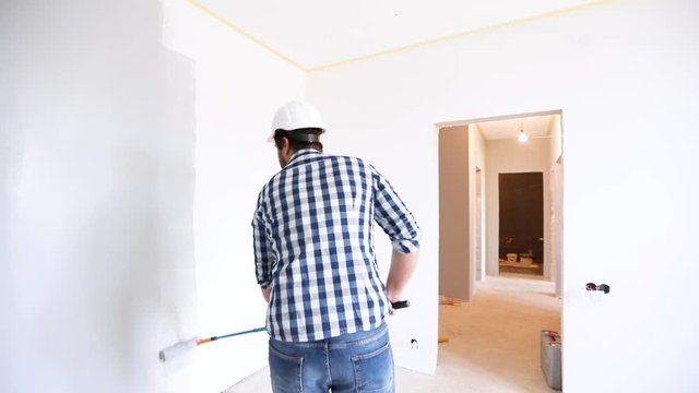 painter manually rolling the grey paint on the wall, apartment renovation