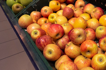 Yellow and red apples in a green box on the counter close-up.