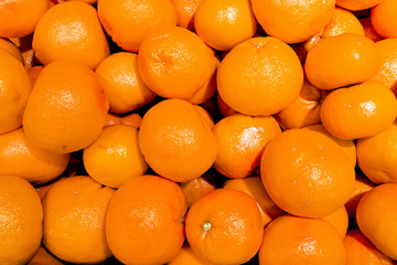 A pile of bright tangerines is laid out on the counter in the store. The concept of the beginning of the new year, the replenishment of vitamins from a natural product, a culinary ingredient, sun, war