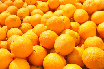 A pile of bright, juicy oranges is laid out on the counter in the store. The concept of replenishing vitamins from a natural product, a culinary ingredient, sun, warmth and summer.