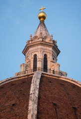 Exterior / facade of the Cathedral of Santa Maria del Fiore in Florence, Italy. Closer look onto a part of the dome with cupola's peak and a cross