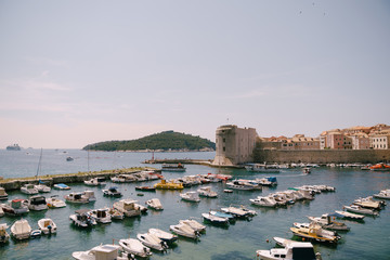 Fototapeta na wymiar The old port harbor is porporela, near the walls of the old town of Dubrovnik, Croatia. Moored boats and yachts near the city.
