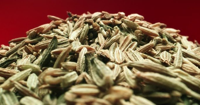 Extreme Macro Shot of Cumin Seeds Rotating Red Background