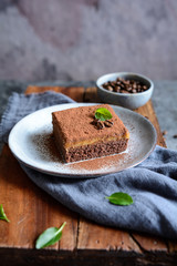 Dark chocolate dessert topped with coffee cream and sprinkled with cocoa powder