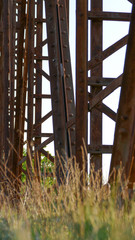 Obraz premium An old disused rusted brown bridge in the countryside connecting two banks across a river, formerly used for busy agricultural traffic