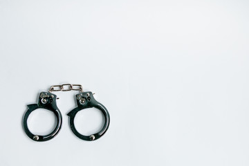 Handcuffs on a white background in the lower left corner of the frame. Copy space. The concept of...