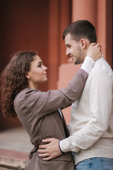 Portrait of beautiful young couple walking outdoors. Hansomen man with attractive woman in the city. Moman with curly hair