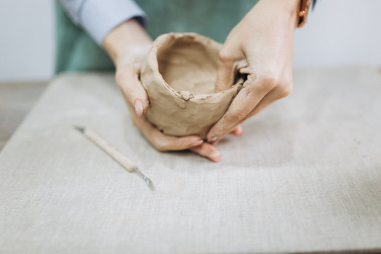 The potter's hands are shaped a cup from a clay. The process of creating pottery. The master ceramist works in his studio. Close-up, only hands. Crockery from clay own hands.	