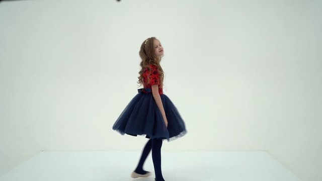 A little girl in a dress is spinning.