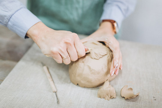 The potter's hands are shaped a cup from a clay. The process of creating pottery. The master ceramist works in his studio. Close-up, only hands. Crockery from clay own hands.	