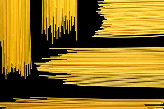 raw pasta, spaghetti on a black background, pattern